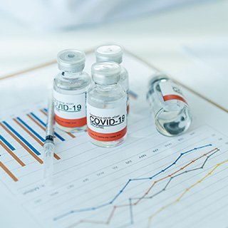 Image of vaccine bottles and syringes on top of data chart